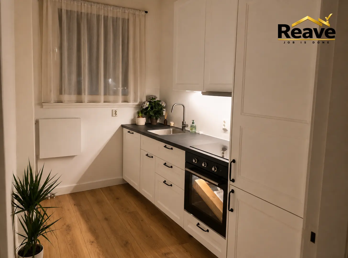 Cream shaker kitchen with dark worktop and oak plank flooring