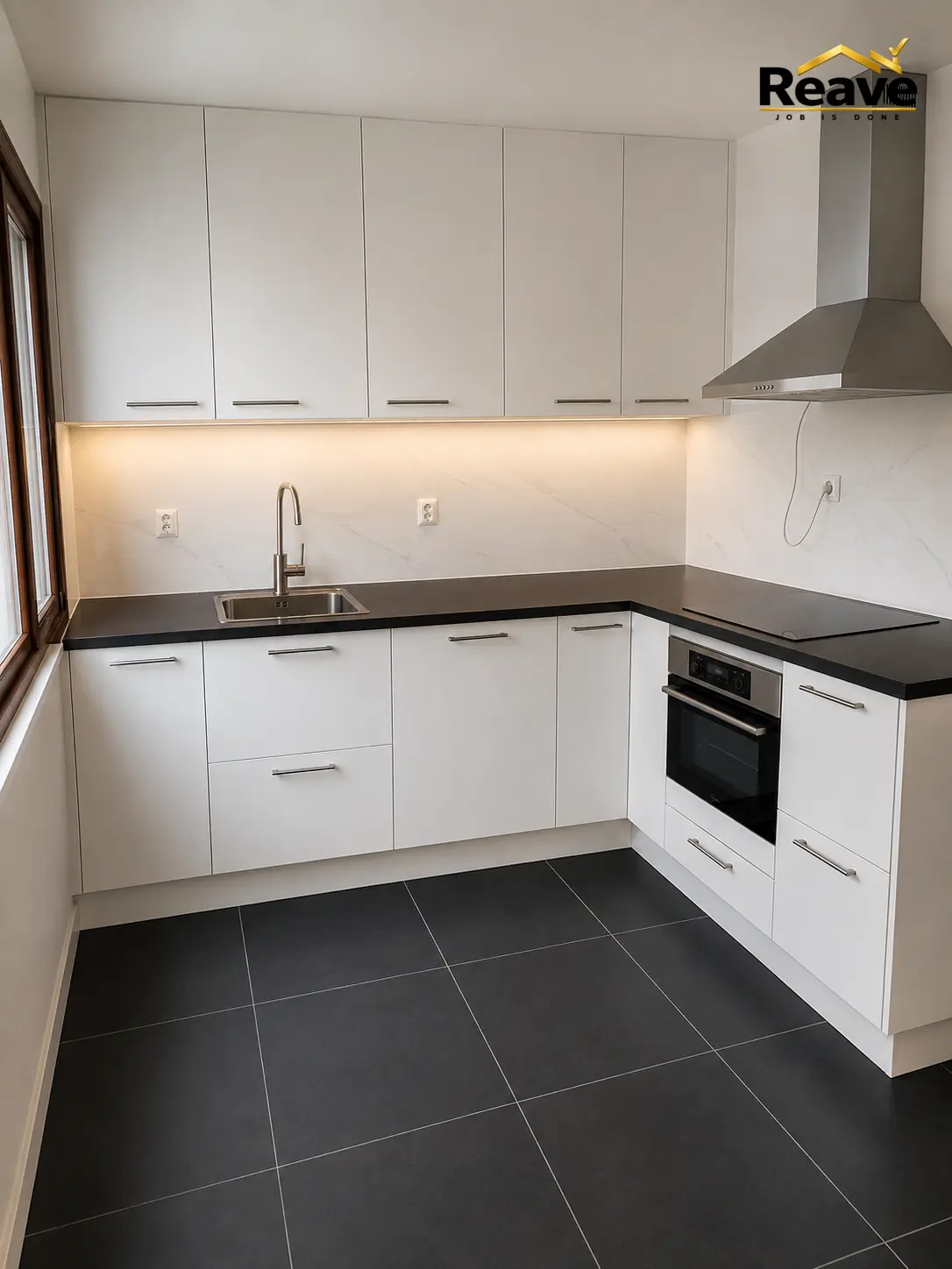 White handleless kitchen with black worktop, marble splashback and stainless extractor