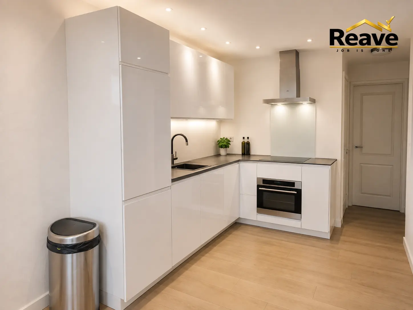 Compact gloss white L-shaped kitchen with dark worktop and built-in oven