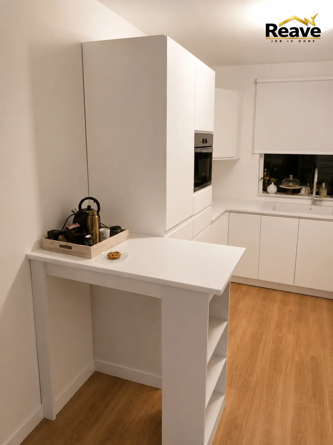 Compact white kitchen with breakfast bar and integrated oven under a sloped ceiling
