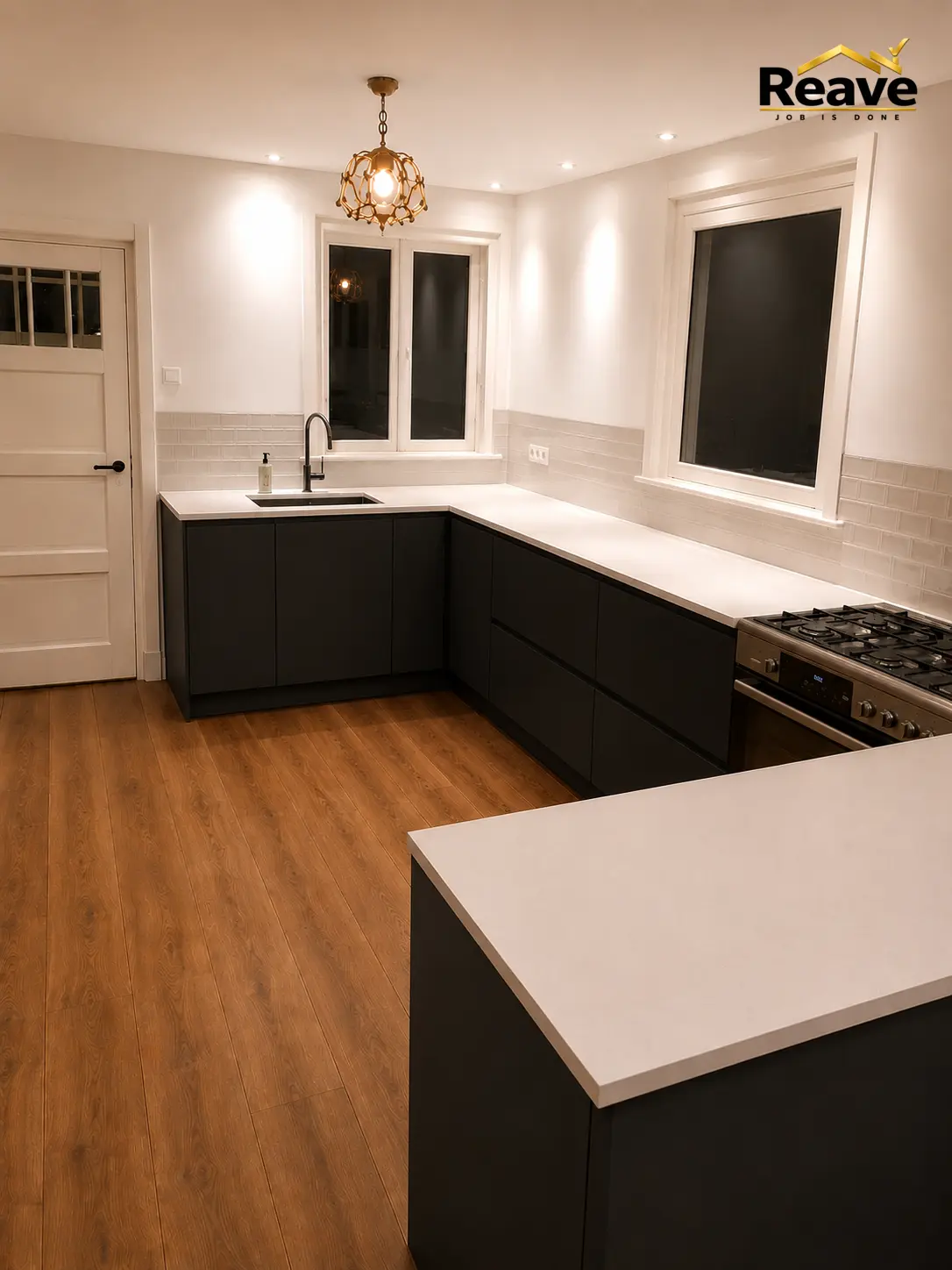 Matte black U-shaped kitchen with white worktop and brass pendant light