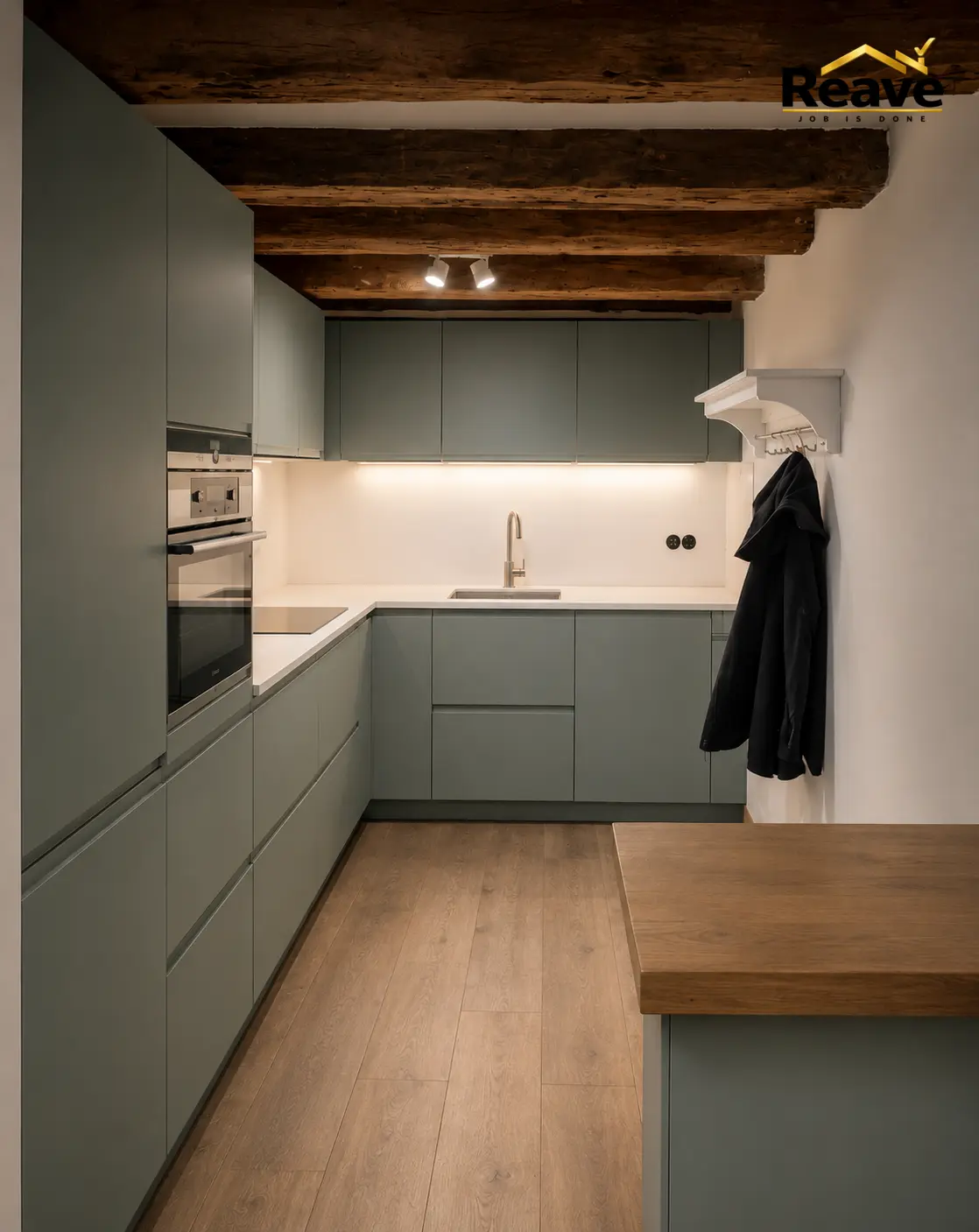 Sage green kitchen under exposed timber beams with oak flooring