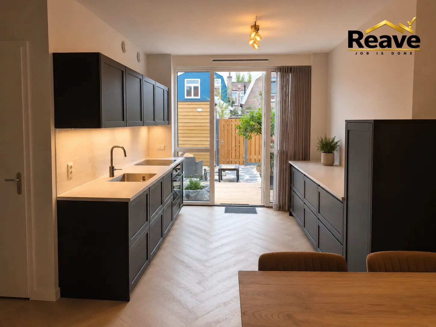 Dark grey galley kitchen with herringbone flooring and garden doors