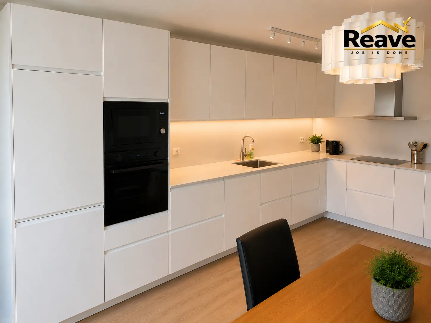 Cream handleless kitchen with integrated black oven and under-cabinet lighting