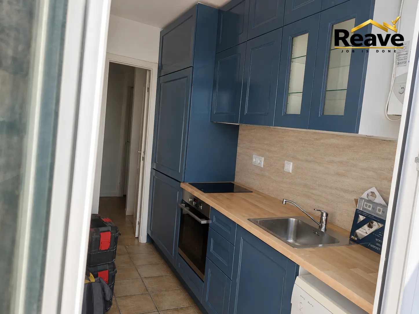Petrol blue shaker galley kitchen with oak worktop and stone-effect splashback