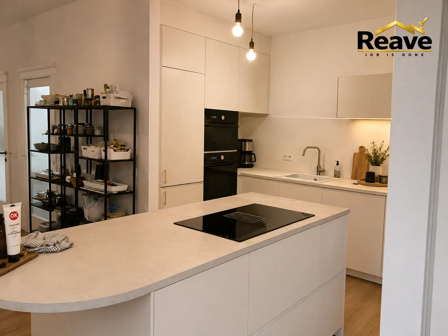 Cream handleless kitchen with curved island, induction hob and double oven