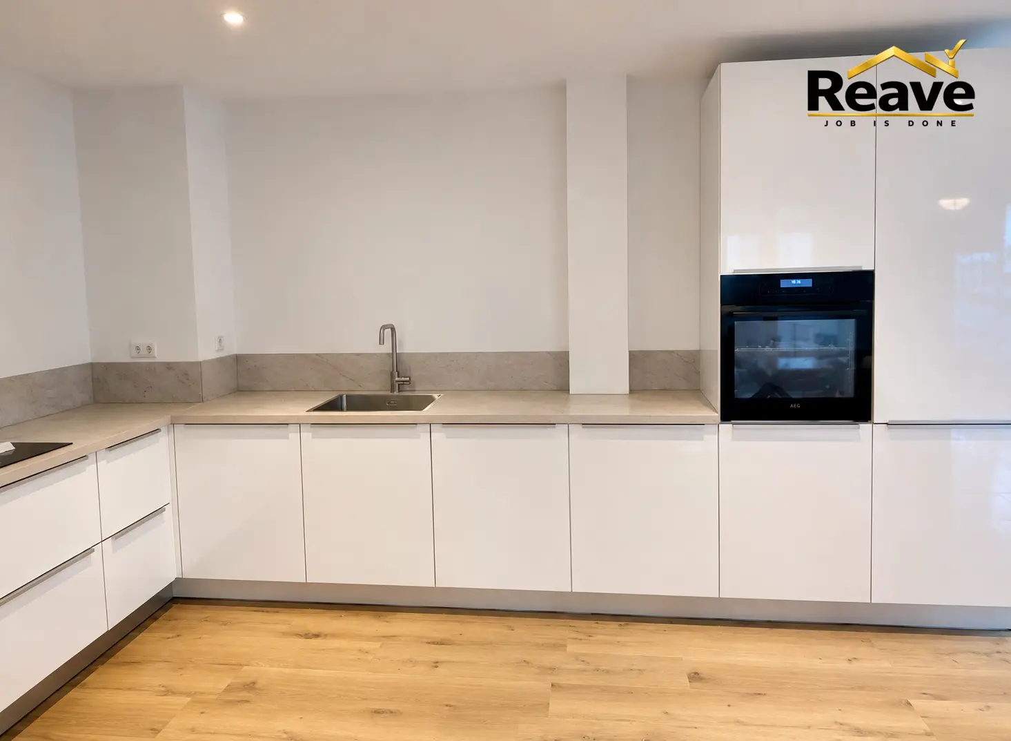 Gloss white kitchen with stone splashback and tall oven housing